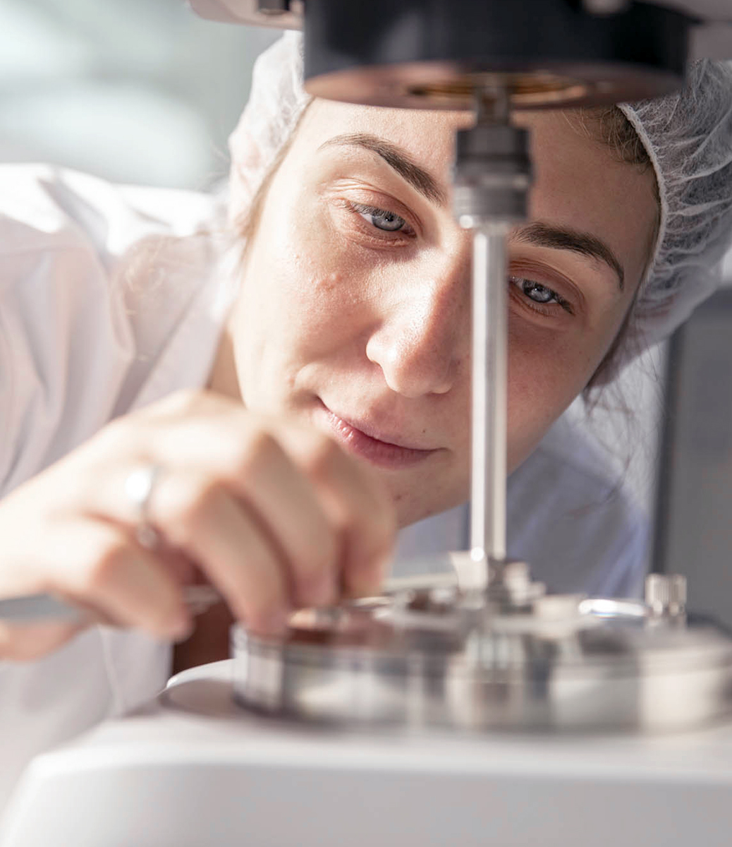Tecnico di laboratorio in camice bianco esegue un'operazione di precisione su uno strumento scientifico.